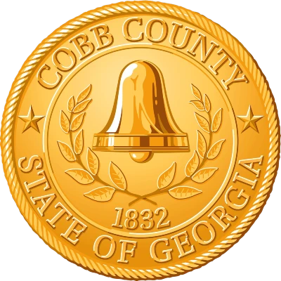 logo of cobb county in georgia. A circuilar coin like design in golden color with a bell and leaves around it. Since 1832